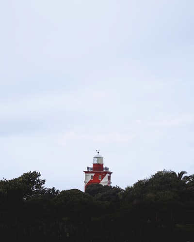 The red and white lighthouse on the top of the hill
